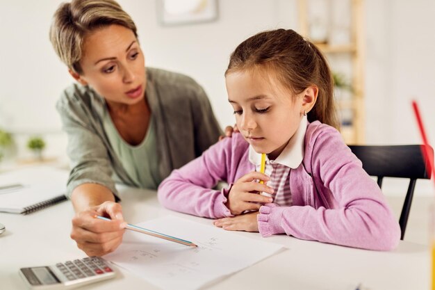 家で学びながら母親と一緒に数学を勉強している小さな女の子