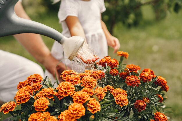 Маленькая девочка со старшей бабушкой, занимающейся садоводством в саду на заднем дворе. Ребенок в белой шляпе.