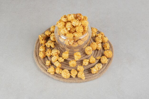 대리석에 캐러멜 코팅 팝콘으로 둘러싸인 니트 삼발이에 작은 유리 그릇.
