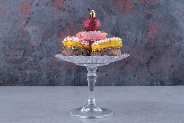 Small glass pedestal with a stack of donuts on marble surface