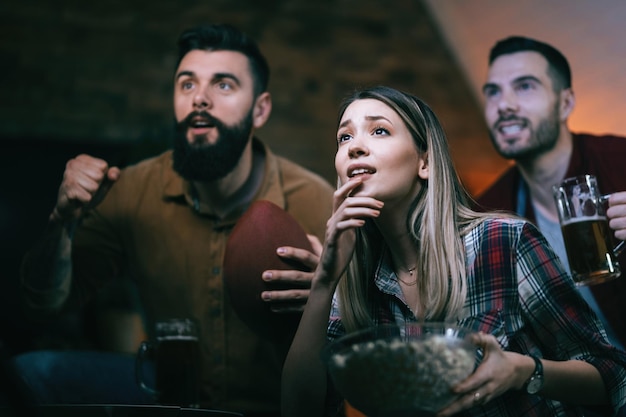 Small group of friends anticipating the end of a rugby match while watching game on TV