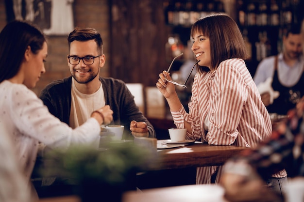 カフェに座ってコーヒーを飲みながらコミュニケーションをとる友人の小グループ