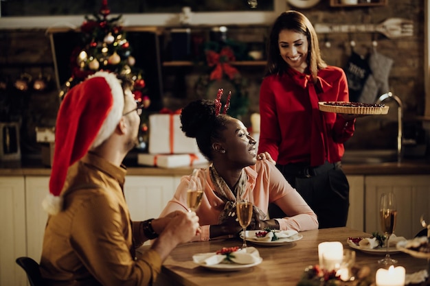 Small group of happy friends enjoying in Christmas dinner at home