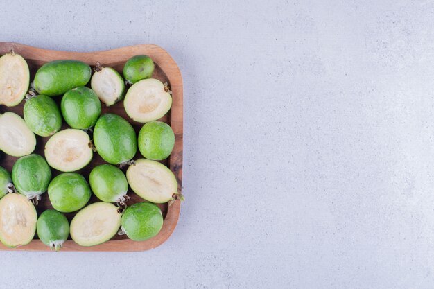 Small heap of feijoas bundled up in a wooden tray on marble background. High quality photo