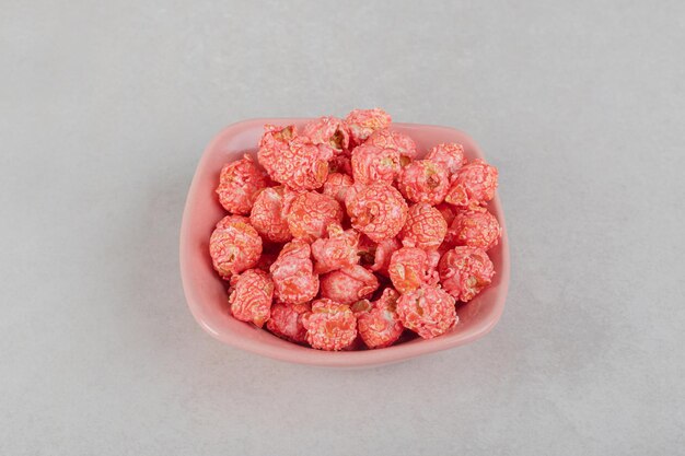 A small heap of flavored popcorn on a pink platter on marble table.