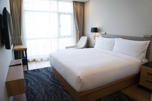 Small hotel bedroom with white walls and panoramic window. 