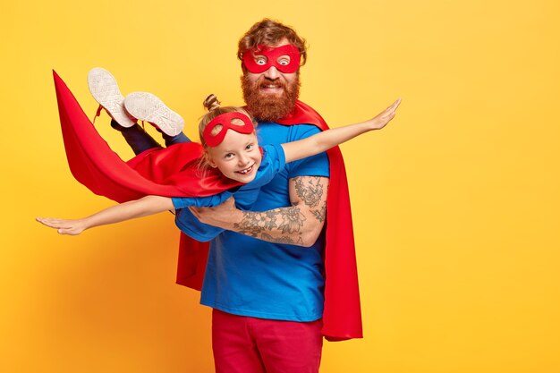 small kid plays superhero, being on fathers hands, pretends flying