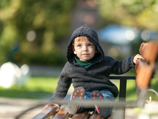 Small little boy sitting on a bench 