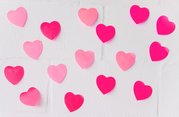 Small paper hearts on white wall 