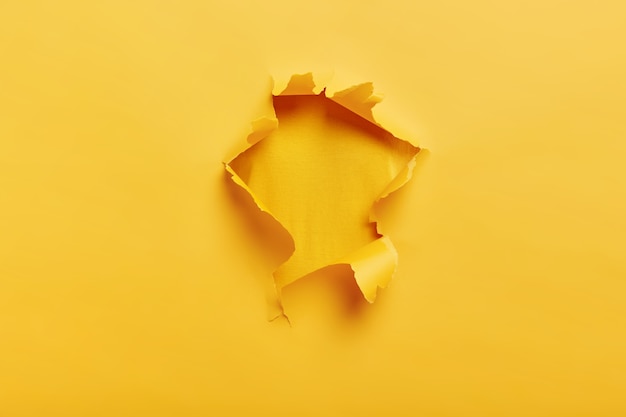 Small paper hole with torn sides over yellow space for your text