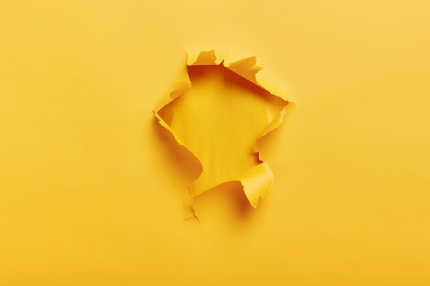 Small paper hole with torn sides over yellow space for your text