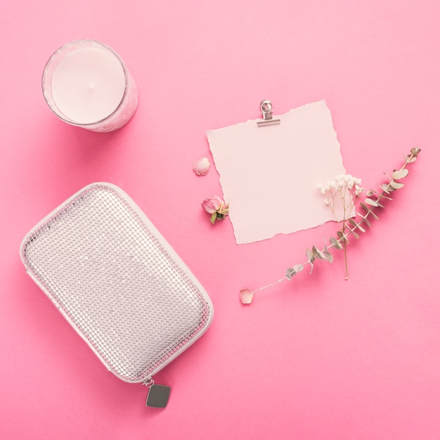 Small paper with branches, candle and clutch on table