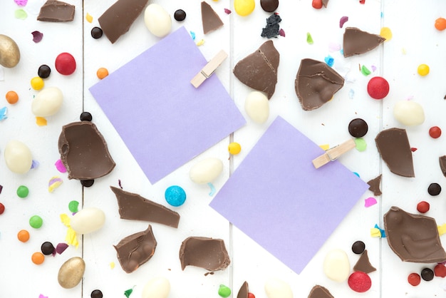 Small papers with cracked chocolate and candies on table