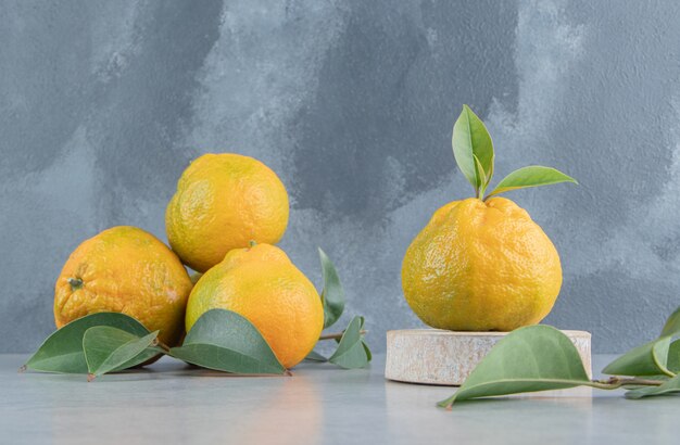 Small pile of tangerines and leaves on marble . 