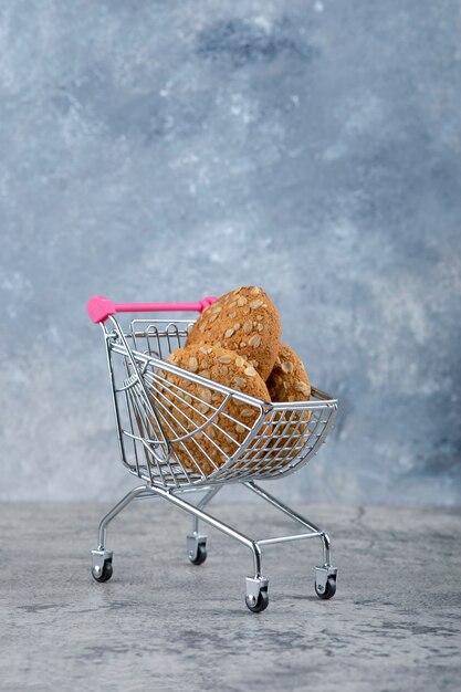 A small pink cart with healthy oatmeal cookies placed on a stone table.