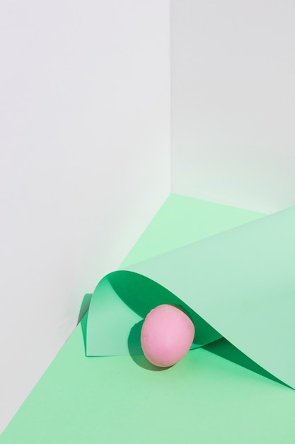 Small pink Easter egg with paper sheet on table