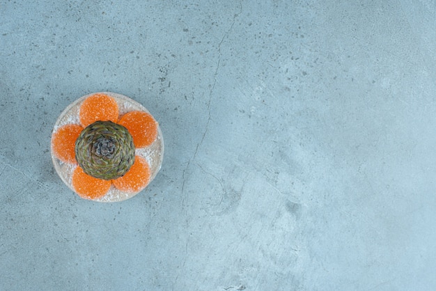Бесплатное фото Блюдо из сосновой шишки и мармелад на мраморе.