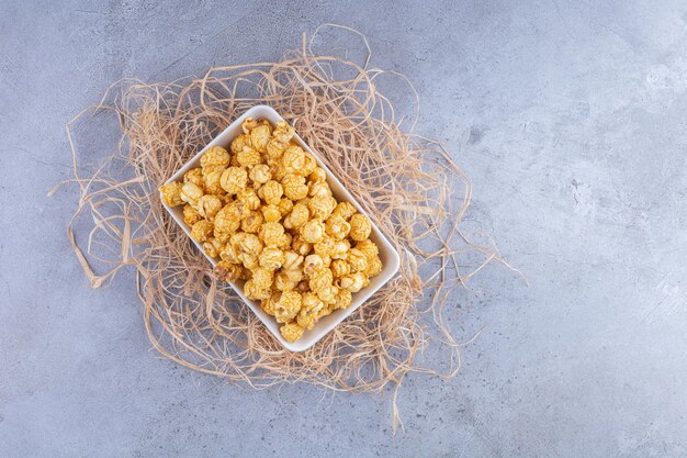 Small platter of popcorn candy on a pile of straws on marble surface