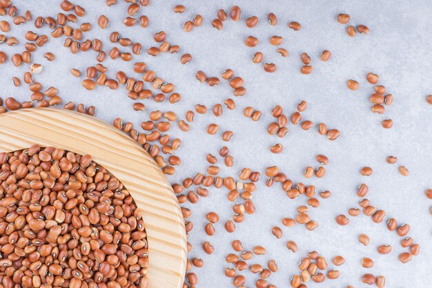 Small platter of red beans placed on top of a scattered pile on marble surface