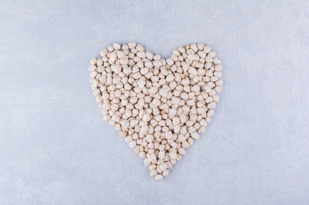 Small portion of chickpeas arranged into a heart shape on marble surface