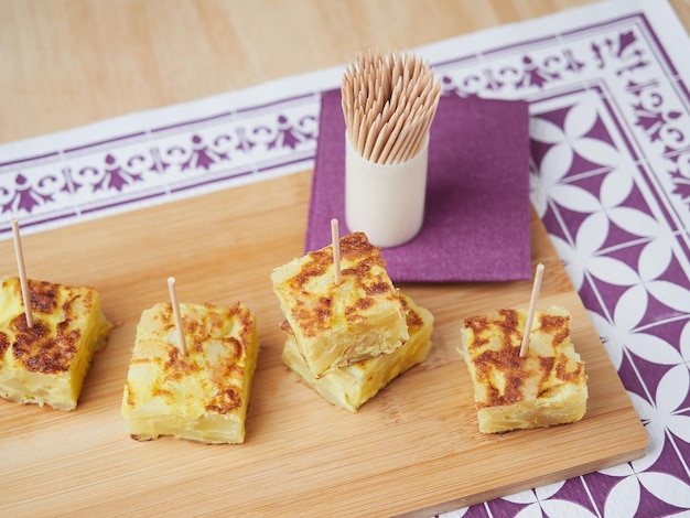 Small portions of potato omelet served as typical spanish tapas with chopsticks called pinchos