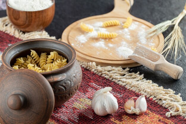 A small pot of unprepared spiral macaroni with garlic and flour