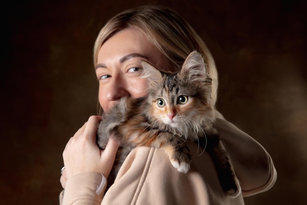 A small purebred kitten sitting on the shoulder of a young woman