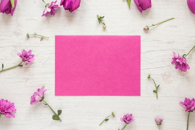 Foto gratuita piccoli fiori viola con carta sul tavolo