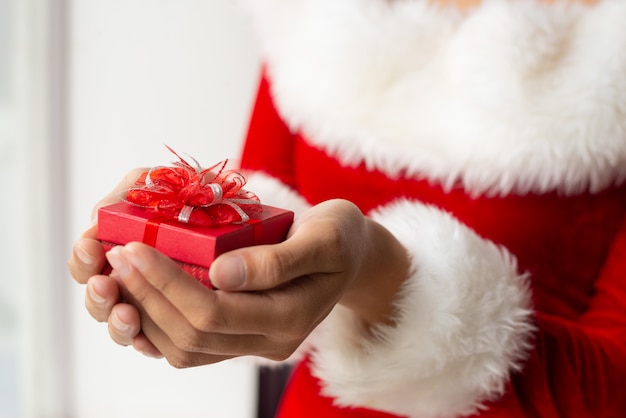 Small red gift box with lacy bow in female hands