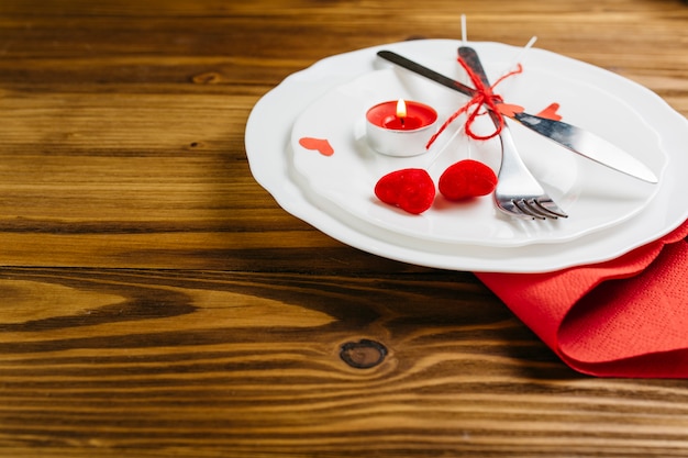 Маленькие красные сердца с столовыми приборами на тарелке