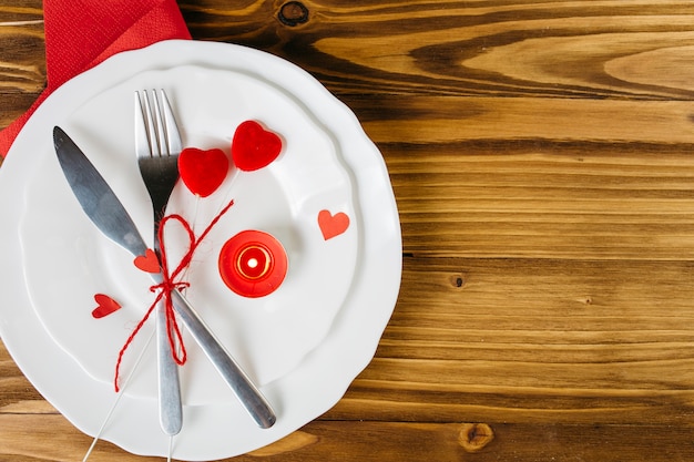 Small red hearts with cutlery on white plate