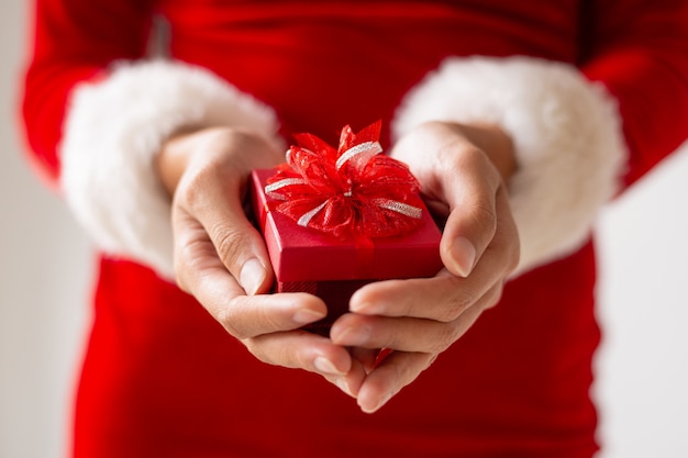 女性の手で弓と小さな赤いプレゼントボックス