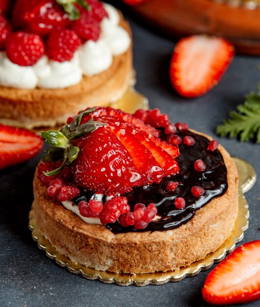 Small round pie decorated with chocolate cream and strawberries