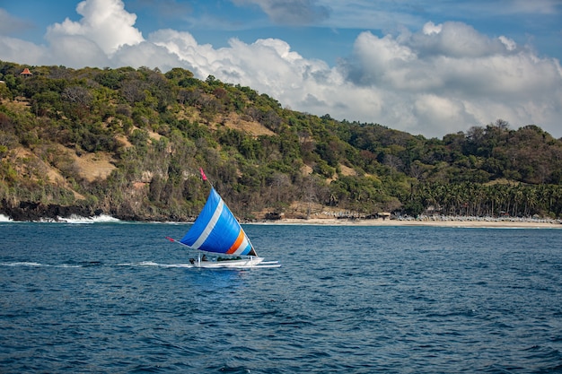 Piccola barca a vela galleggia sull'acqua con viste mozzafiato sulle montagne.