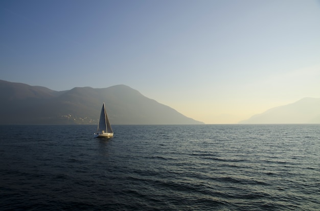 Small sailing boat in the lake with the sunset