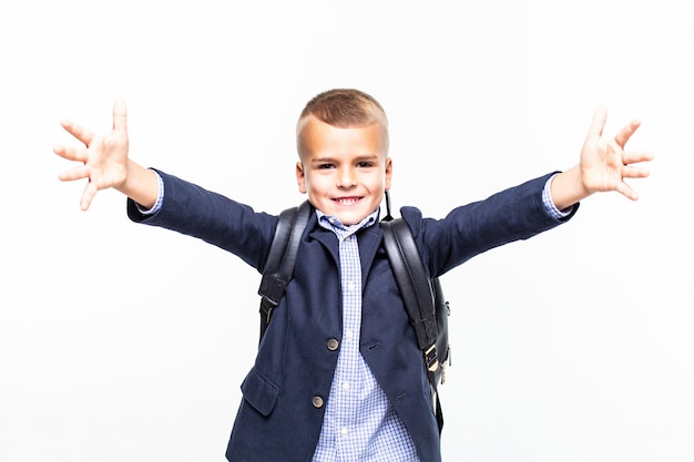 Foto gratuita piccolo ragazzo di scuola che fa posa divertente sulla parete bianca