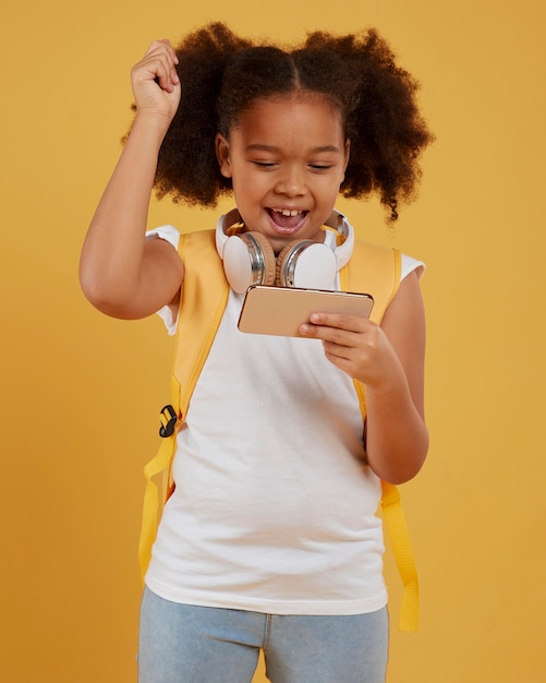 Foto gratuita piccola ragazza della scuola che gioca sul telefono cellulare