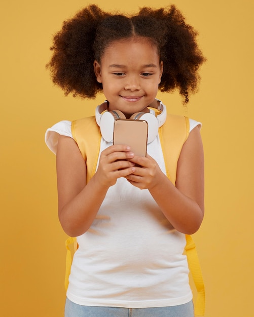 Foto gratuita piccola ragazza della scuola utilizzando il telefono cellulare