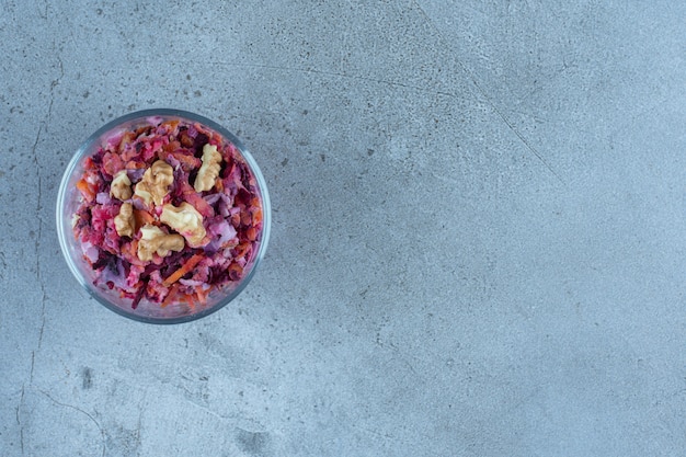 Small serving bowl of beet and walnut salad in a small on marble table.