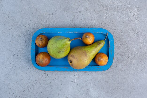 A small serving of pears on a blue platter on marble background. 