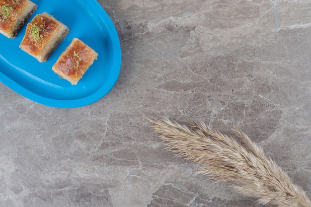 Free photo small serving of turkish bakhlavas and feather grass stalks on marble surface