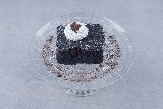 Бесплатное фото Небольшой кусочек шоколадного торта на стеклянном блюде на мраморе