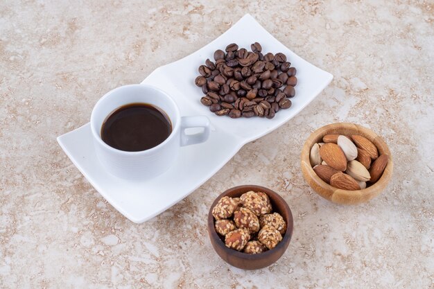 Маленькие миски для закусок рядом с кучей кофейных зерен и чашкой кофе