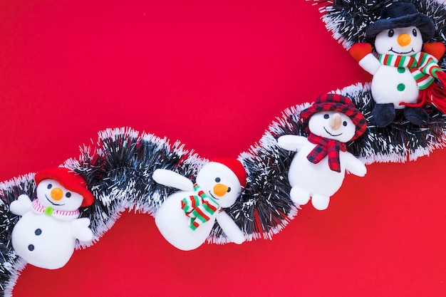 Small snowmen on tinsel on red table