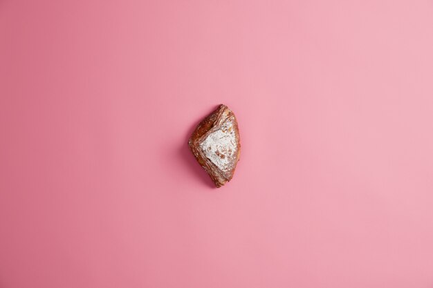 Small sweet fresh soft baked bun sparkled with sugar, isolated on pink background. Confectionery baking. Delicious dessert for breakfast or dinner. Unhealthy eating, food containing much calories