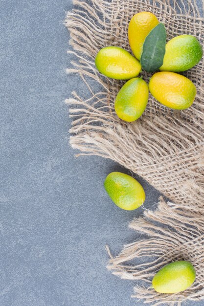 Small tangerines with burlap on marble.