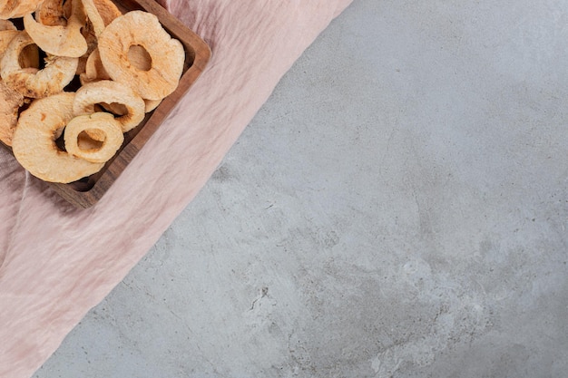 Small tray of fried apple rings on concrete table.