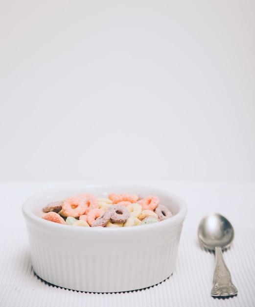 朝食用シリアルループと白い背景に対してスプーンの小さな白いボウル