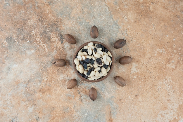 Free photo a small wooden bowl full of raisin and nuts on marble background