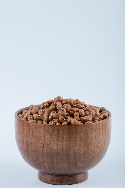 A small wooden bowl full of raw brown kidney beans